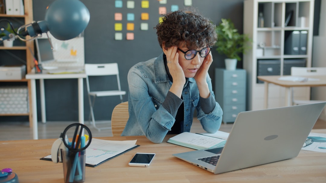 An overwhelmed employee sitting at a laptop during a demanding workday